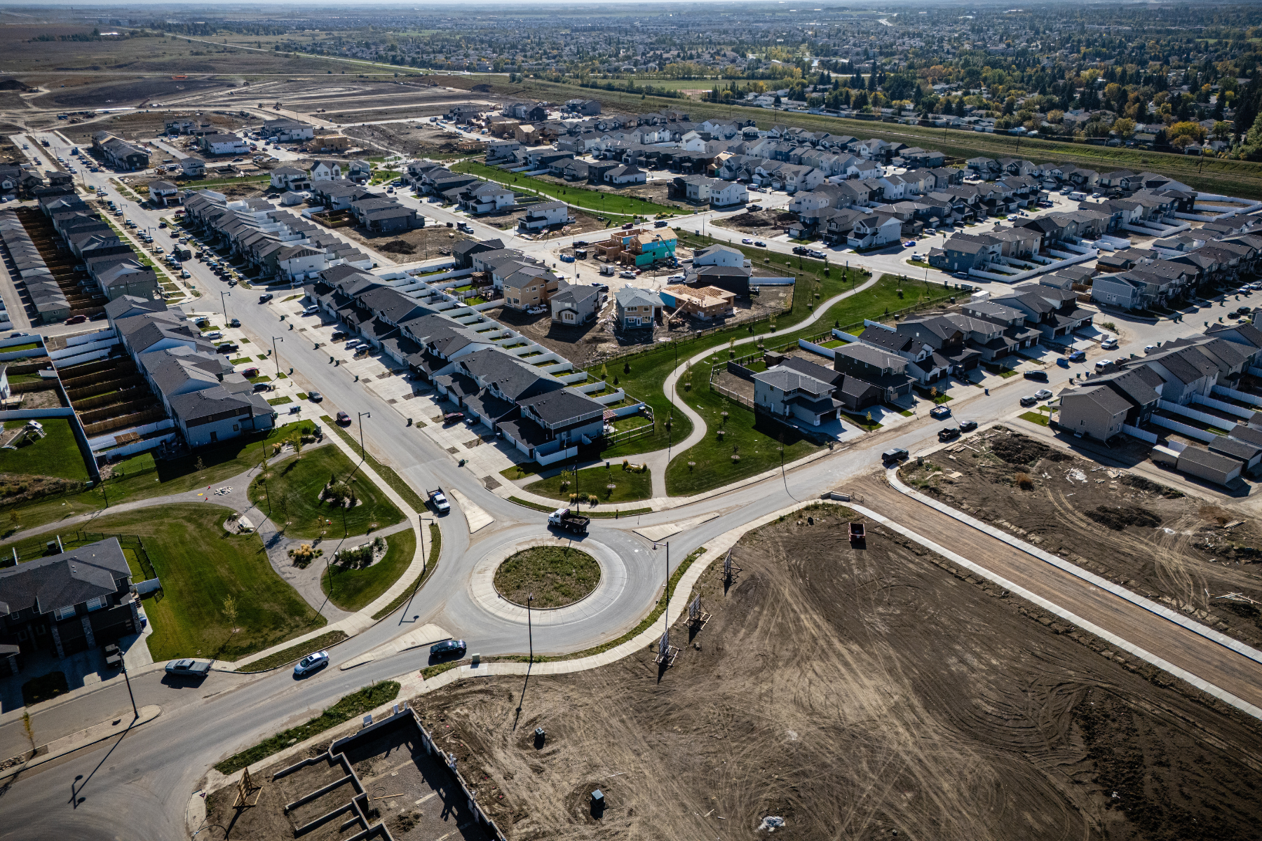 Drone aerial of Brighton, Saskatoon, featuring modern homes, wetlands, and suburban streets