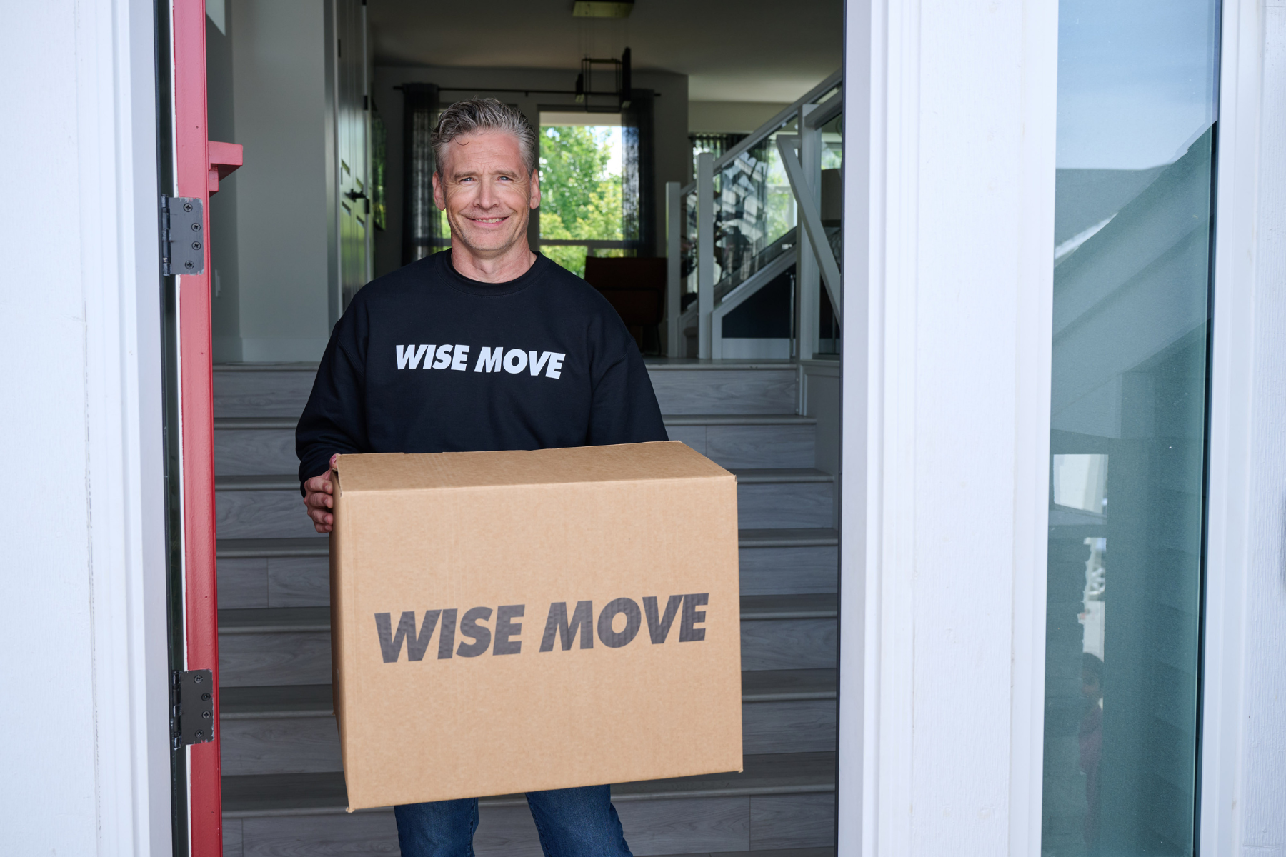 Professional mover carrying a moving box into a contemporary house