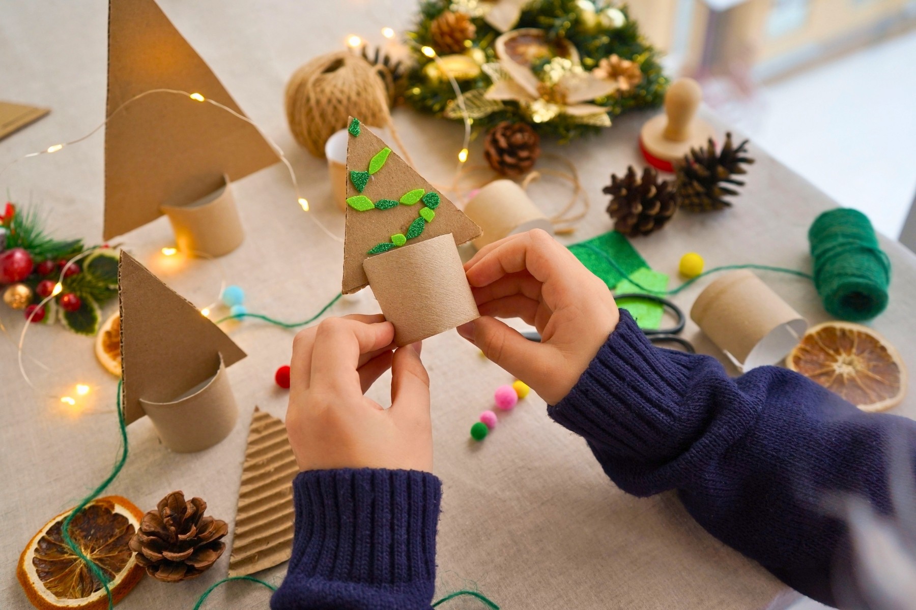 Child making DIY Christmas tree decor from cardboard